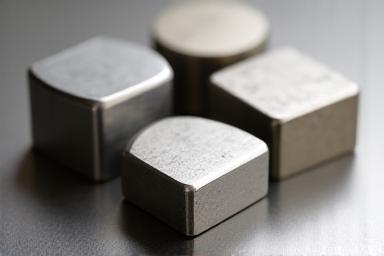 Assorted polished billets of different metals, including titanium and steel.